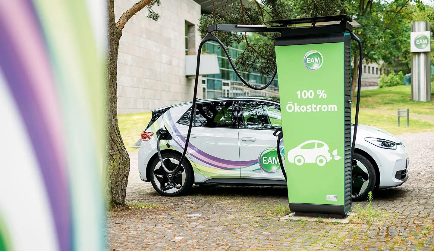 Elektroauto lädt an einer Ladestation mit dem Hinweis 100 % Ökostrom im Freien."