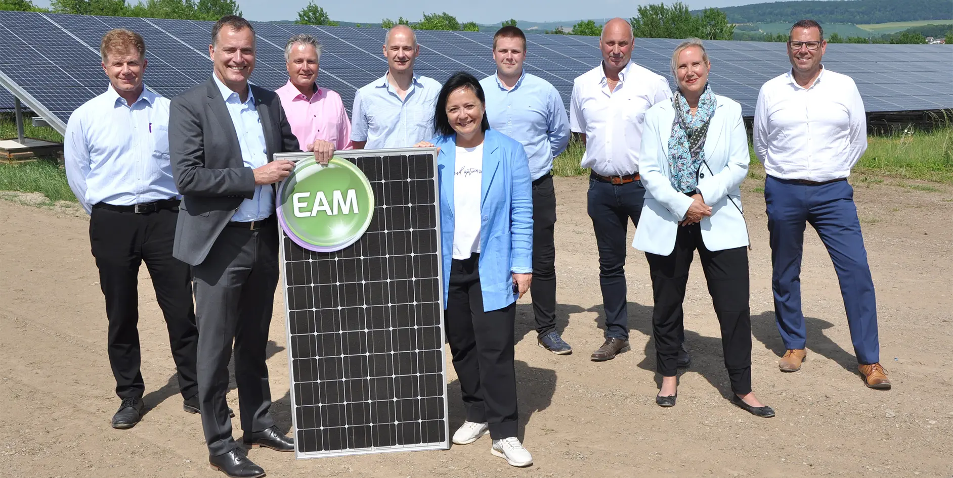 Gruppenzusammenkunft von Fachleuten vor einer Solaranlage mit einem Solarpanel und dem Logo EAM.