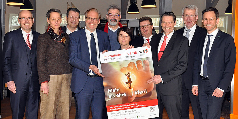 Gruppe von Personen hält ein Plakat zum Innovationspreis 2018 des Landkreises Göttingen, alle lächeln und schauen in die Kamera.