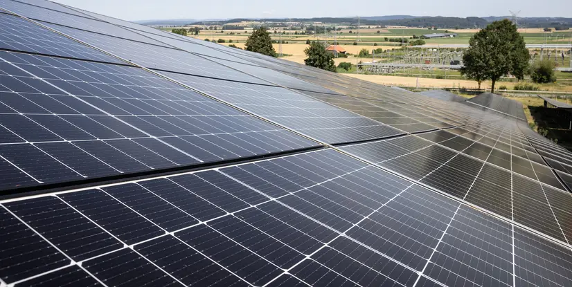 Solaranlage auf einem Dach, mit mehreren Solarzellen, im Hintergrund eine ländliche Landschaft.