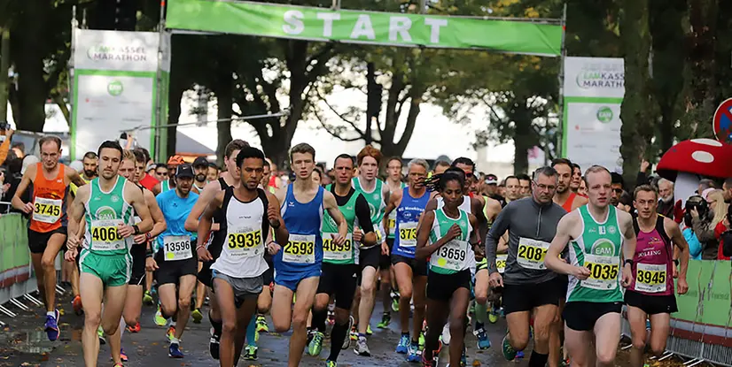 Start des Kasseler Marathons mit laufenden Teilnehmern in Sportbekleidung und Zuschauern im Hintergrund.