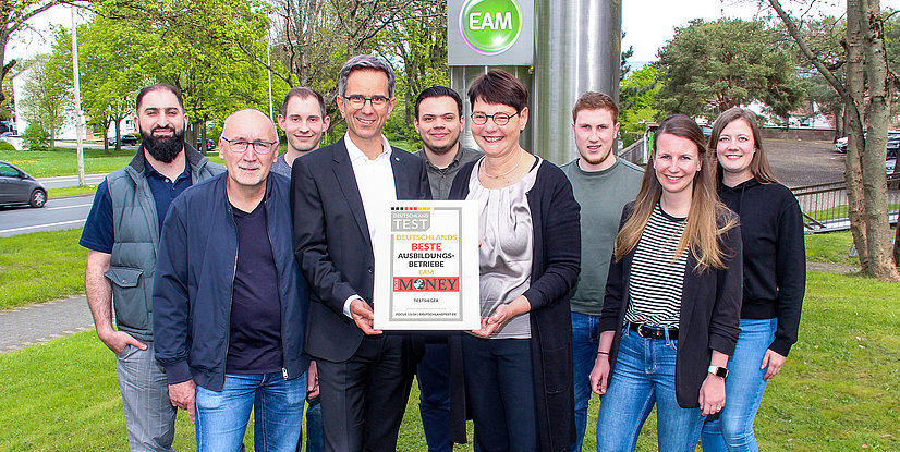 Teamfoto mit Auszeichnung für die besten Ausbildungsbetriebe in Deutschland, präsentiert vor dem EAM-Logo.