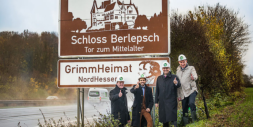 Vier Personen in Sicherheitshelmen stehen lächelnd neben einem Schild mit der Aufschrift Schloss Berlepsch – Tor zum Mittelalter.