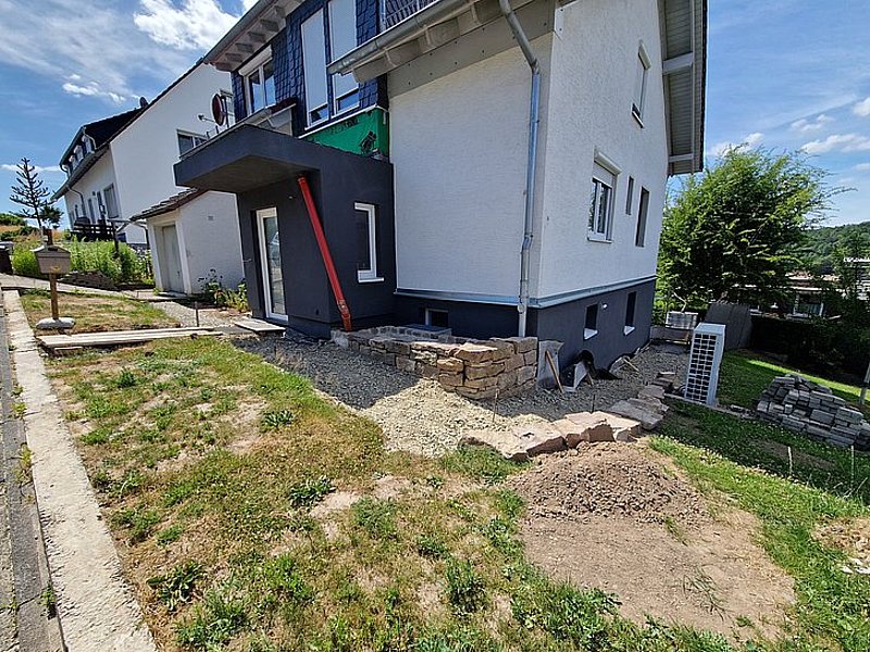 Neubau eines Wohnhauses mit Seitenansicht, Gartenbereich und unvollendeter Landschaftsgestaltung.