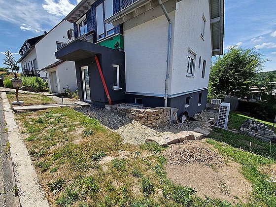 Neubau eines Wohnhauses mit Seitenansicht, Gartenbereich und unvollendeter Landschaftsgestaltung.