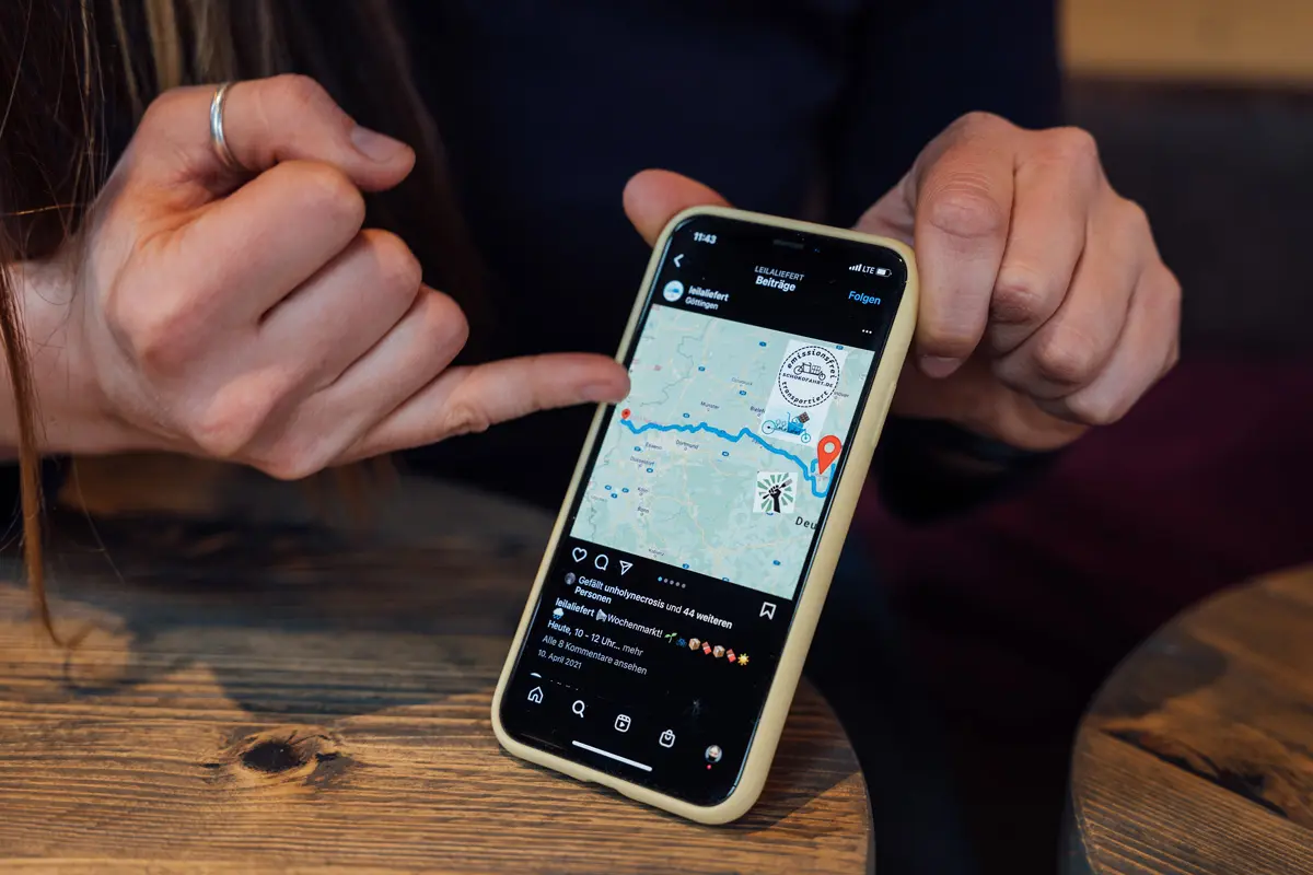 Eine Person zeigt auf eine Karte auf einem Smartphone, das eine Route zwischen zwei Punkten anzeigt.