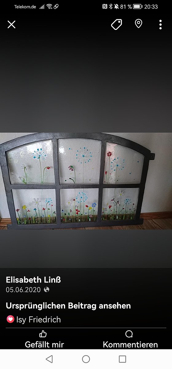 Bunt bemalte Glasscheiben, die Blumenmuster und eine grüne Wiese darstellen, in einem geschwungenen Rahmen.