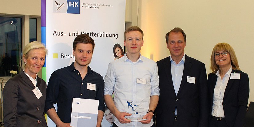 Fünf Personen stehen vor einem Banner der IHK Kassel-Marburg, das Informationen zur Aus- und Weiterbildung präsentiert.