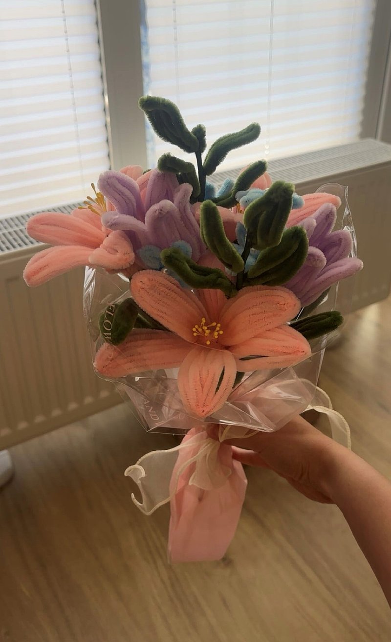 Ein buntes Blumenbouquet aus Stoff mit zarten Blüten in Rosa, Violett und Blau, verpackt in transparentem Folie.