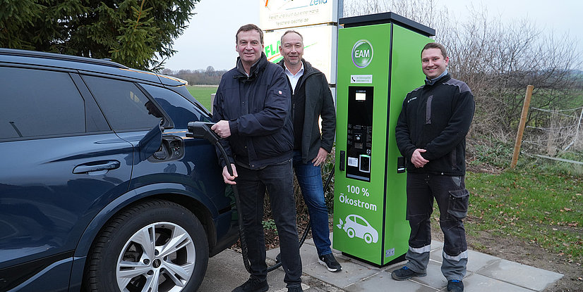 Martin Bechtel (Landgasthof Bechtel), der Geschäftsführer der EAM Natur Energie Sven Nuhn und Unimeister Marius Laudenbach vom Regioteam Borken vor einer der beiden neuen Ladesäulen in Willingshausen.