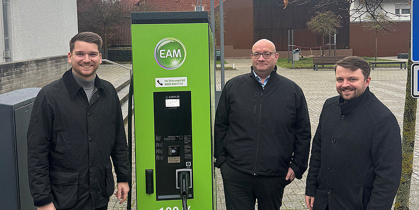 Freuen sich über die neue Ladesäule in Friedewald (v. l. - stehen um die grüne EAM-Ladesäule verteilt und schauen in die Kamera): Bürgermeister Julian Kempka, Michael Bräutigam (EAM Natur Energie / E-Mobilität) und André Jüttner (Vertreter Leiter Netzregion Borken).