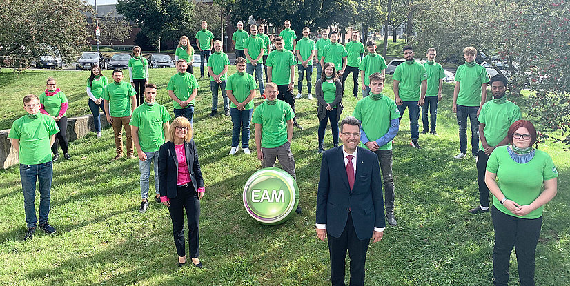 Gruppenfoto von den neuen Auszubildenden der EAM in grünen T-Shirts, stehend im Freien, mit dem EAM-Logo in der Mitte.