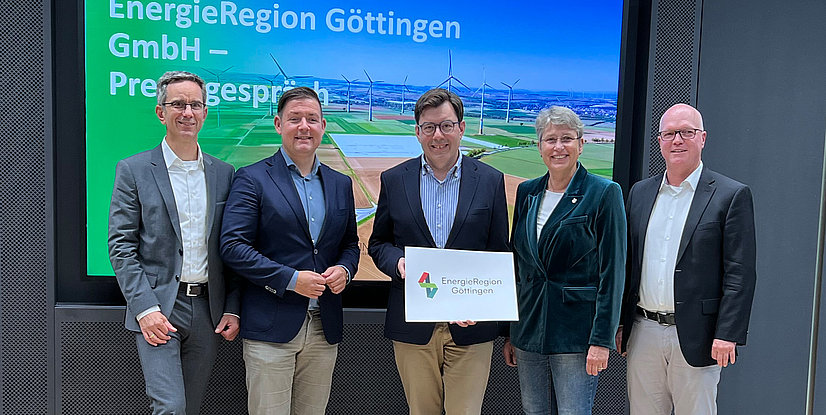 Gruppenfoto von fünf Personen vor einem Bildschirm mit dem Logo der EnergieRegion Göttingen und einer Landschaft mit Windrädern.