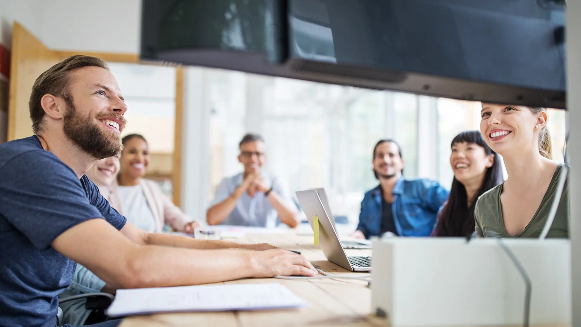  Mitarbeiter:innen in einem modernen Büro lächeln während eines Meetings.