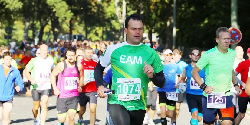 Läufer in bunten Trikots nehmen an einem Marathon teil, zahlreiche Teilnehmer sind im Hintergrund sichtbar.