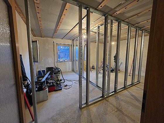 Bauzimmer mit Trockenbauwänden, Werkzeugen und Materialien in einem unfertigen Raum mit Fenster.
