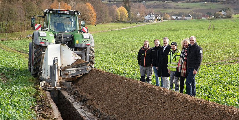 orort-Termin mit Kabelfräse (v. l.): Fräsfahrer Lars Michanikl, der Leiter des Regioteams Biedenkopf Jens Urban, Gladenbachs Bürgermeister Peter Kremer, Ingo Klös von der EN Tiefbau Süd, Bad Endbachs Bürgermeisterin Erika Weber und Leiter der Netzregion Dillenburg/Biedenkopf Marcus Hief.