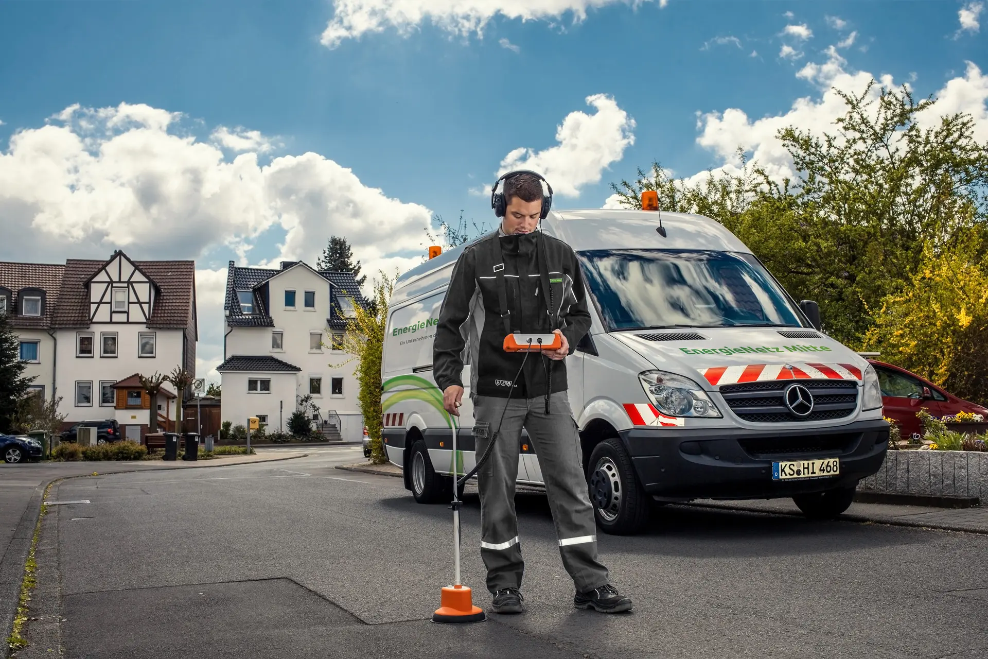 Ein Mitarbeiter von EnergieNetz Mitte, mit Kopfhörern und Messgerät, steht vor einem weißen Transporter.