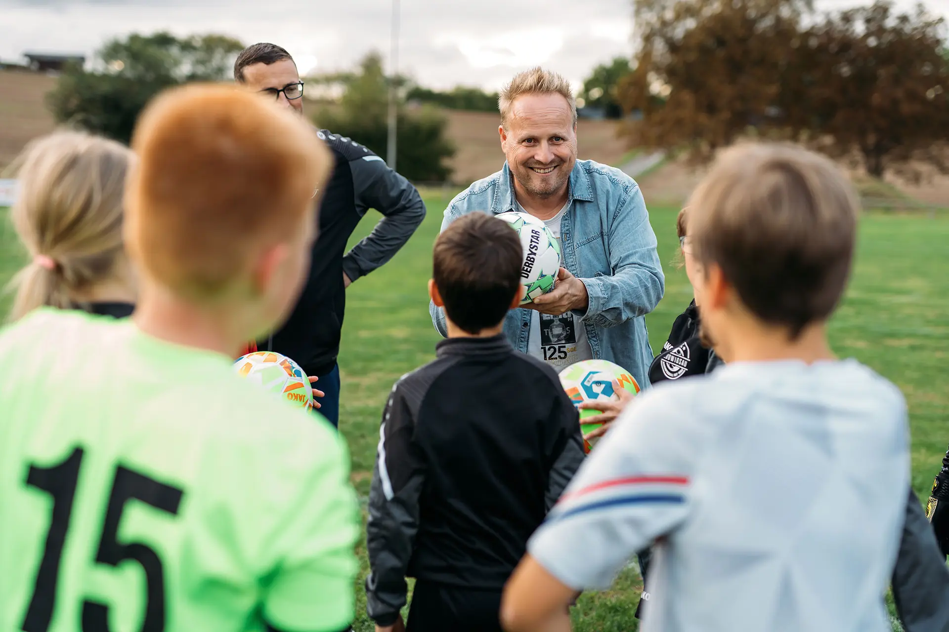 Kinder am Fussballplatz mit dem Trainer
