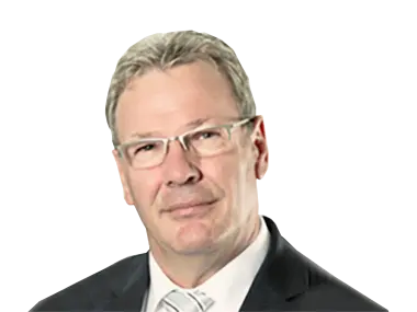 Gerhard Pfeifer Portrait eines Mannes mit Brille und grauen Haaren, in einem schwarzen Anzug und weißem Hemd. Neutraler Hintergrund.