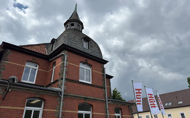 Das Hauptgebäude der Hütt Brauerei in Baunatal mit Logo-Flaggen vor dem Eingang.
