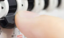 Eine Hand dreht einen Regler an einem elektrischen Schaltschrank für Anpassungen.