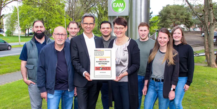 Teamfoto mit Auszeichnung für die besten Ausbildungsbetriebe in Deutschland, präsentiert vor dem EAM-Logo.