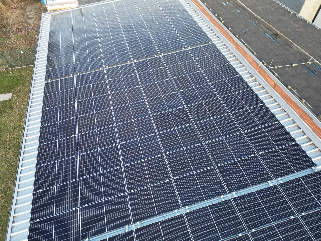 Solaranlage auf einem Dach mit vielen Photovoltaikmodulen, die in einem regelmäßigen Muster angeordnet sind.