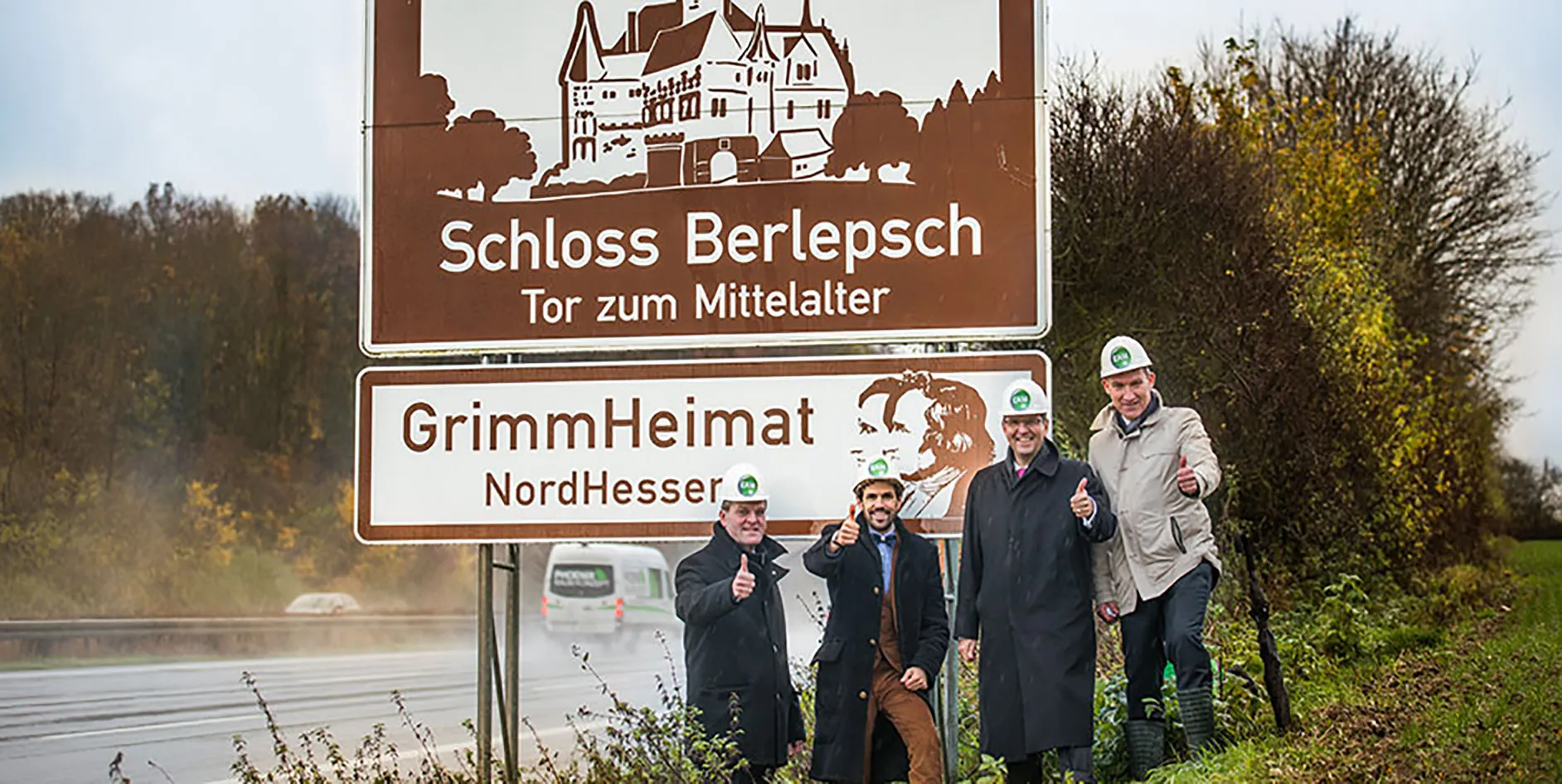 Vier Personen in Sicherheitshelmen stehen lächelnd neben einem Schild mit der Aufschrift Schloss Berlepsch – Tor zum Mittelalter.
