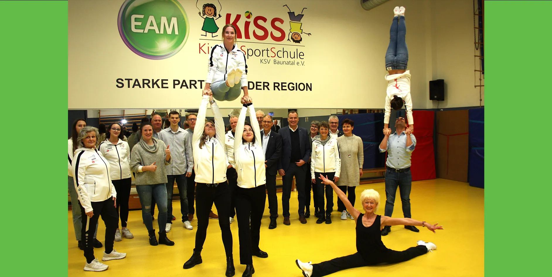 Gruppenszene mit Trainingsaktivitäten in einer Sporthalle, Teilnehmer in sportlicher Kleidung, freudige Gesichter, Fokus auf Akrobatik.