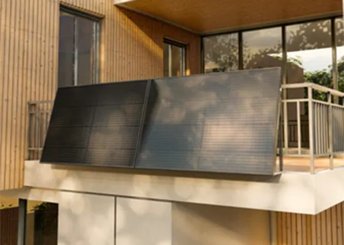 Solaranlage auf einem modernen Balkon eines Holzhauses mit großen Fenstern.