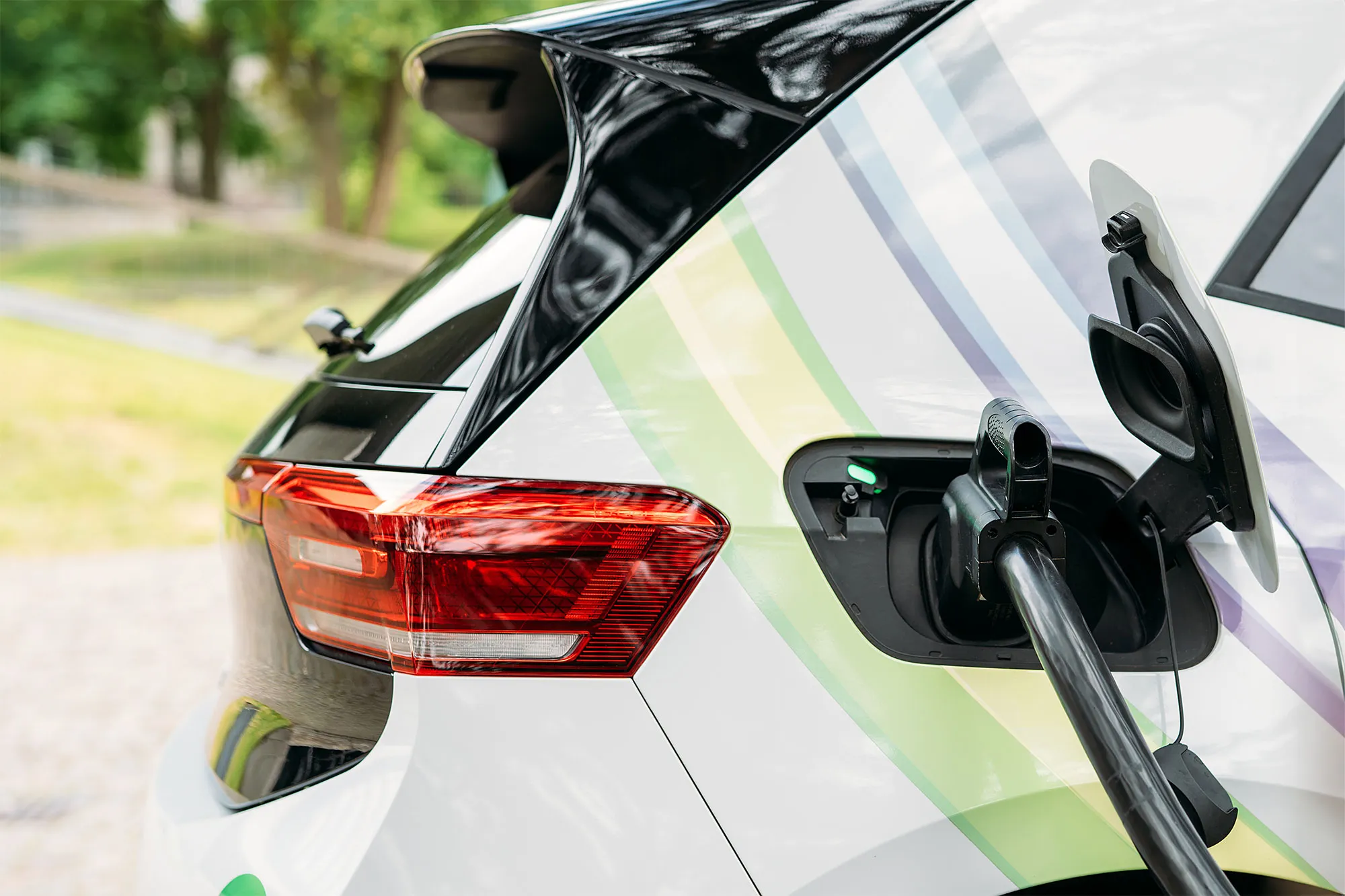 Elektroauto mit geöffnetem Ladeanschluss, das an einer Ladestation aufgeladen wird.