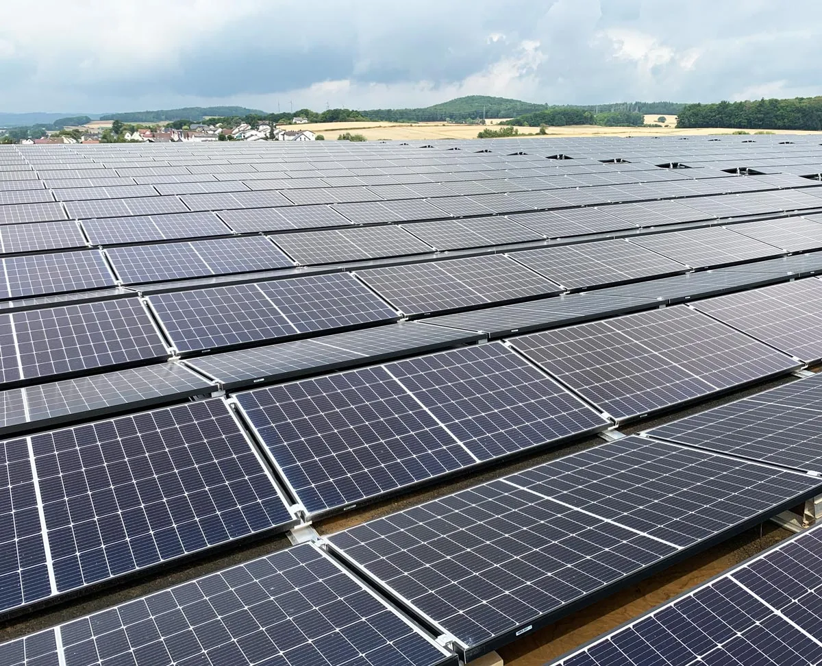 Weite Sicht auf ein Solarkraftwerk mit zahlreichen Sonnenkollektoren unter einem grauen Himmel.