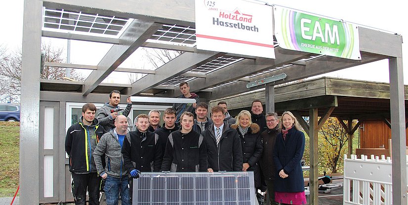 Gruppe von Personen vor einem Holzbau mit Solarpanelen, feierliche Atmosphäre zum Jubiläum von HolzLand Hasselbach.