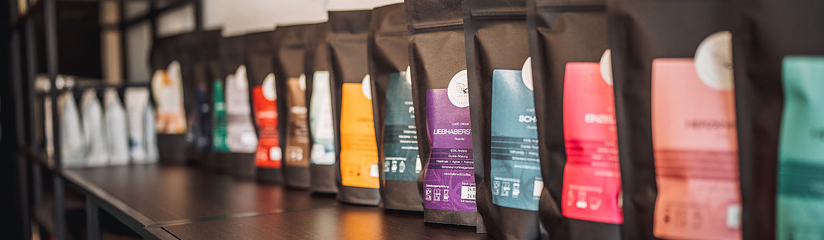 Regal mit verschiedenen Teepackungen in schwarzer Verpackung, jeweils mit unterschiedlichen Farben und Beschriftungen.
