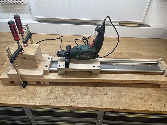 Bild eines werkzeuggestützten Holzprojekts mit einem Bohrer und einer Schiene auf einer Werkbank.