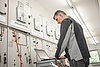 Netzschutztechnik Ein Techniker arbeitet an einer Steuerungstafel mit einem Laptop, um industrielle Systeme zu überprüfen.