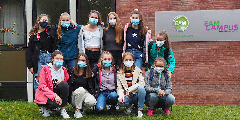 Gruppierung von Jugendlichen, die vor einem Gebäude mit EAM CAMPUS-Schild posieren.