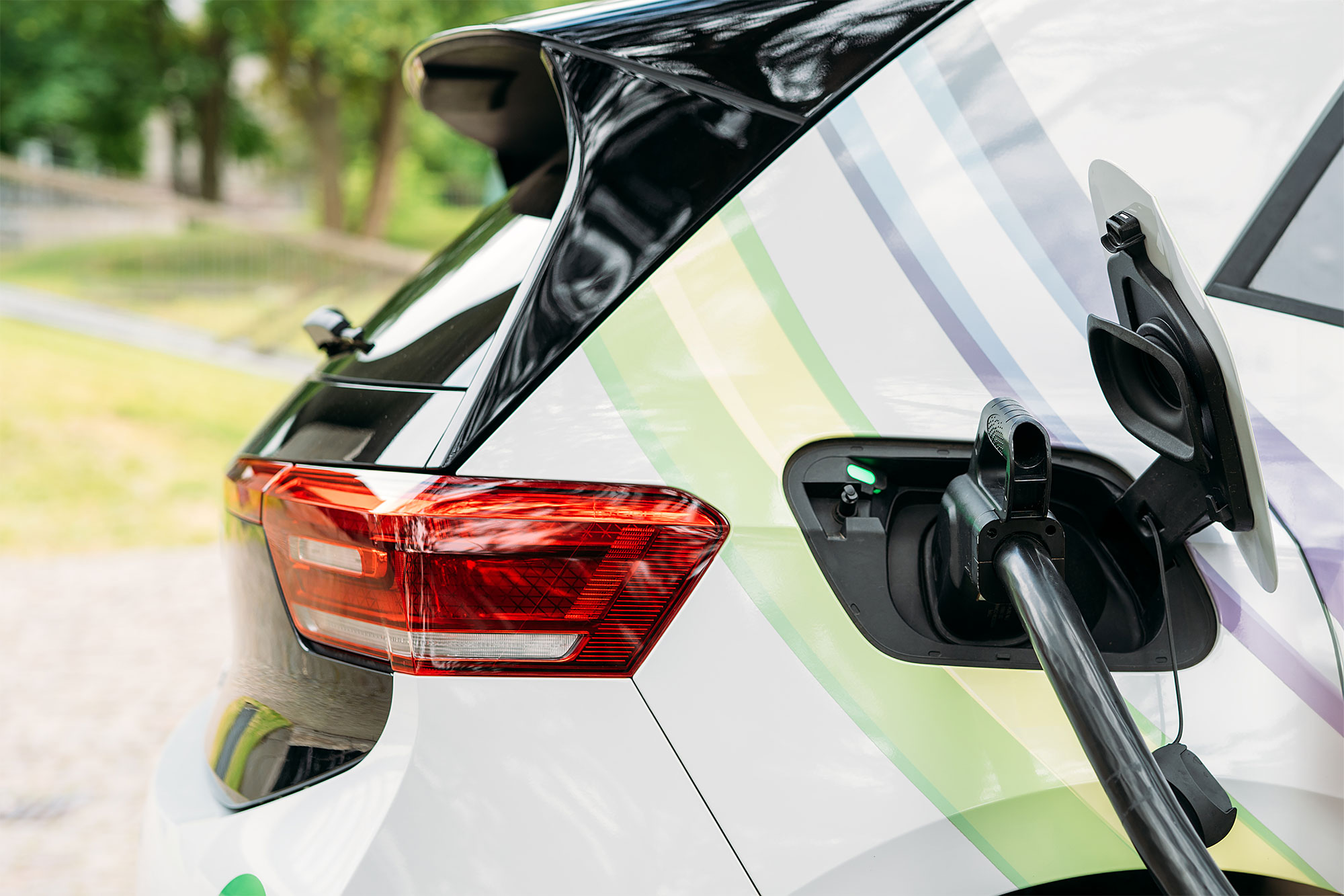 Elektroauto mit geöffnetem Ladeanschluss, das an einer Ladestation aufgeladen wird.