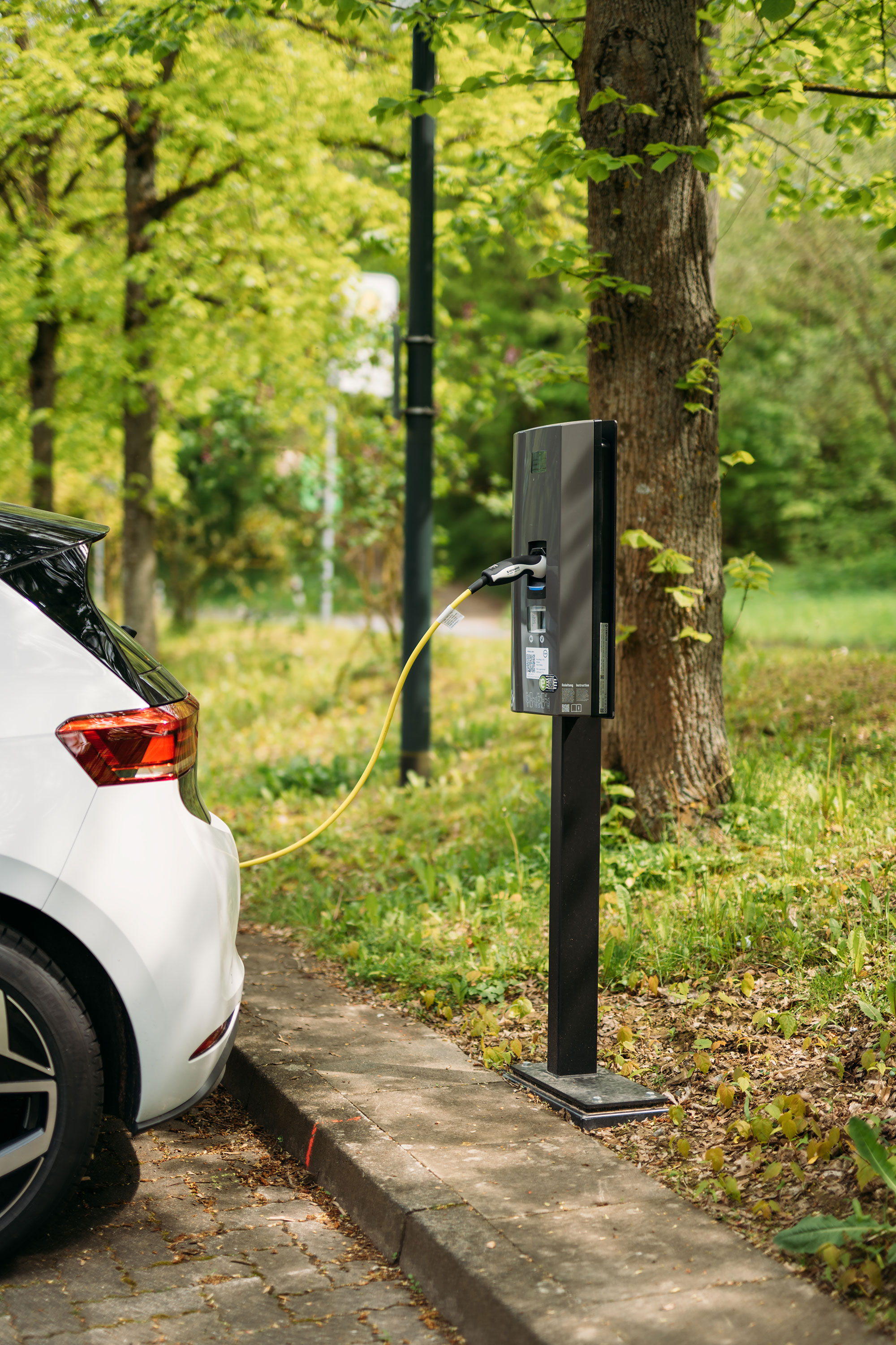 Elektroauto wird an einer Ladestation in einer grünen Umgebung aufgeladen.