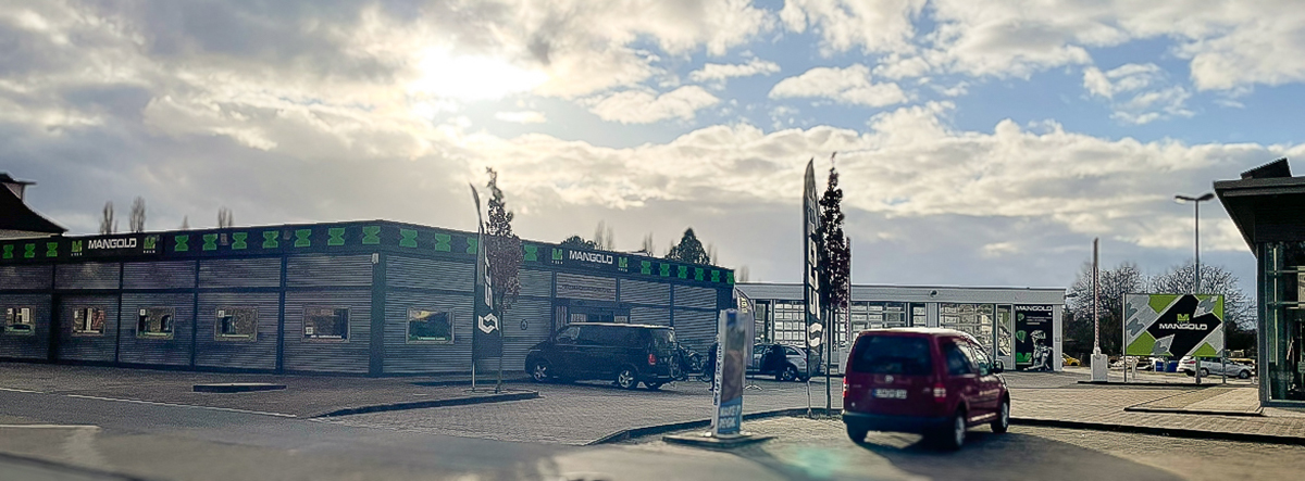 Aufnahme eines modernen Autohauses mit der Beschriftung "MANGOLD"" und sichtbaren Fahnen