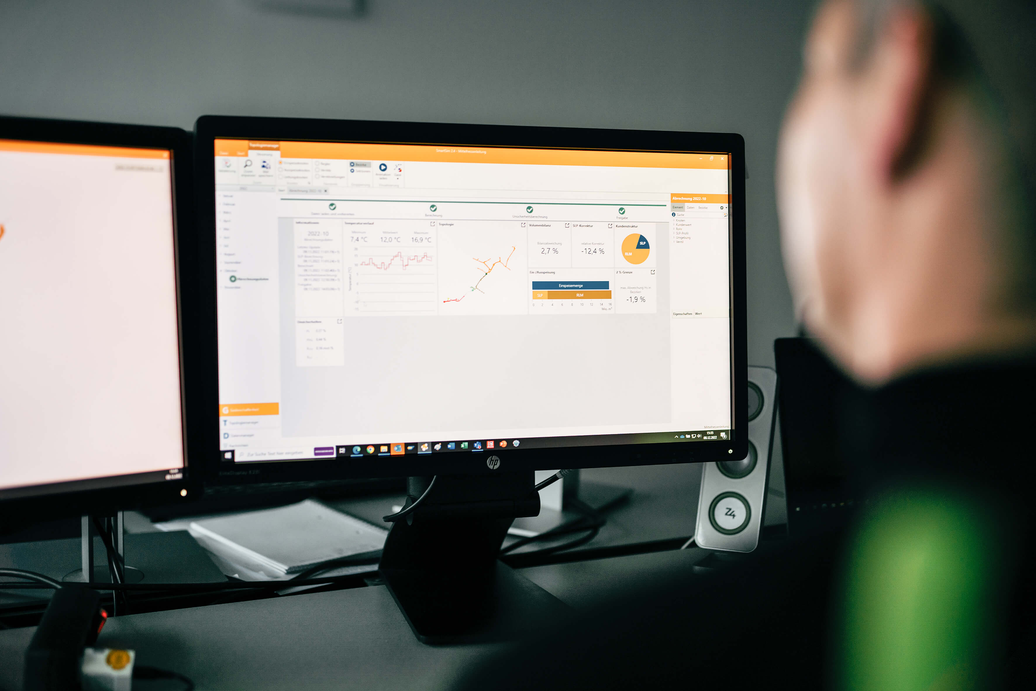 Alt-Tag: Person sieht auf zwei Computerbildschirme mit grafischen Daten und Diagrammen zu Temperatur und Energieverbrauch.