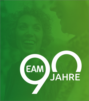 Ein lächelndes Paar vor einem grünen Hintergrund, feiernd das 90-jährige Jubiläum von EAM.