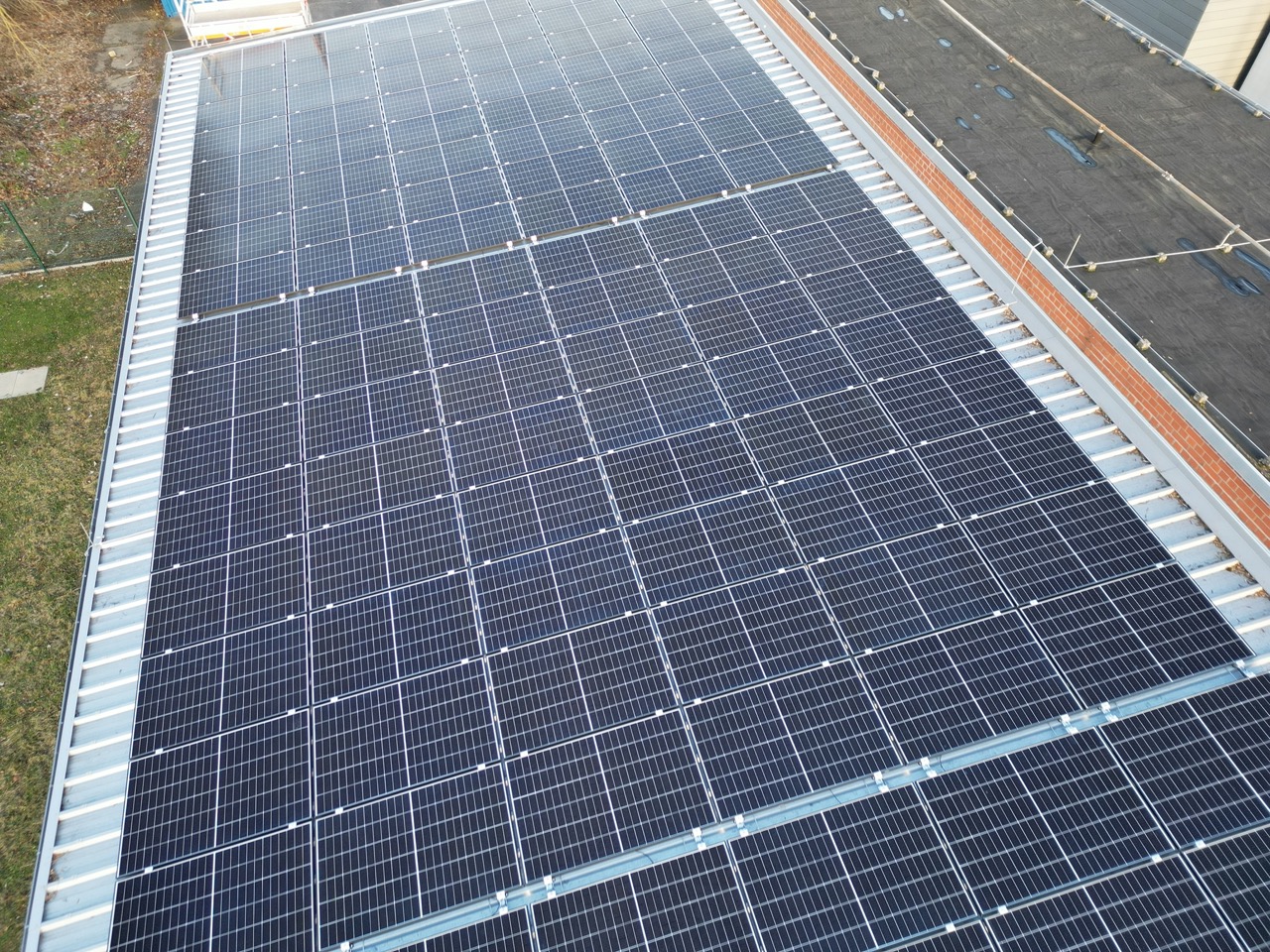 Solaranlage auf einem Dach mit vielen Photovoltaikmodulen, die in einem regelmäßigen Muster angeordnet sind.