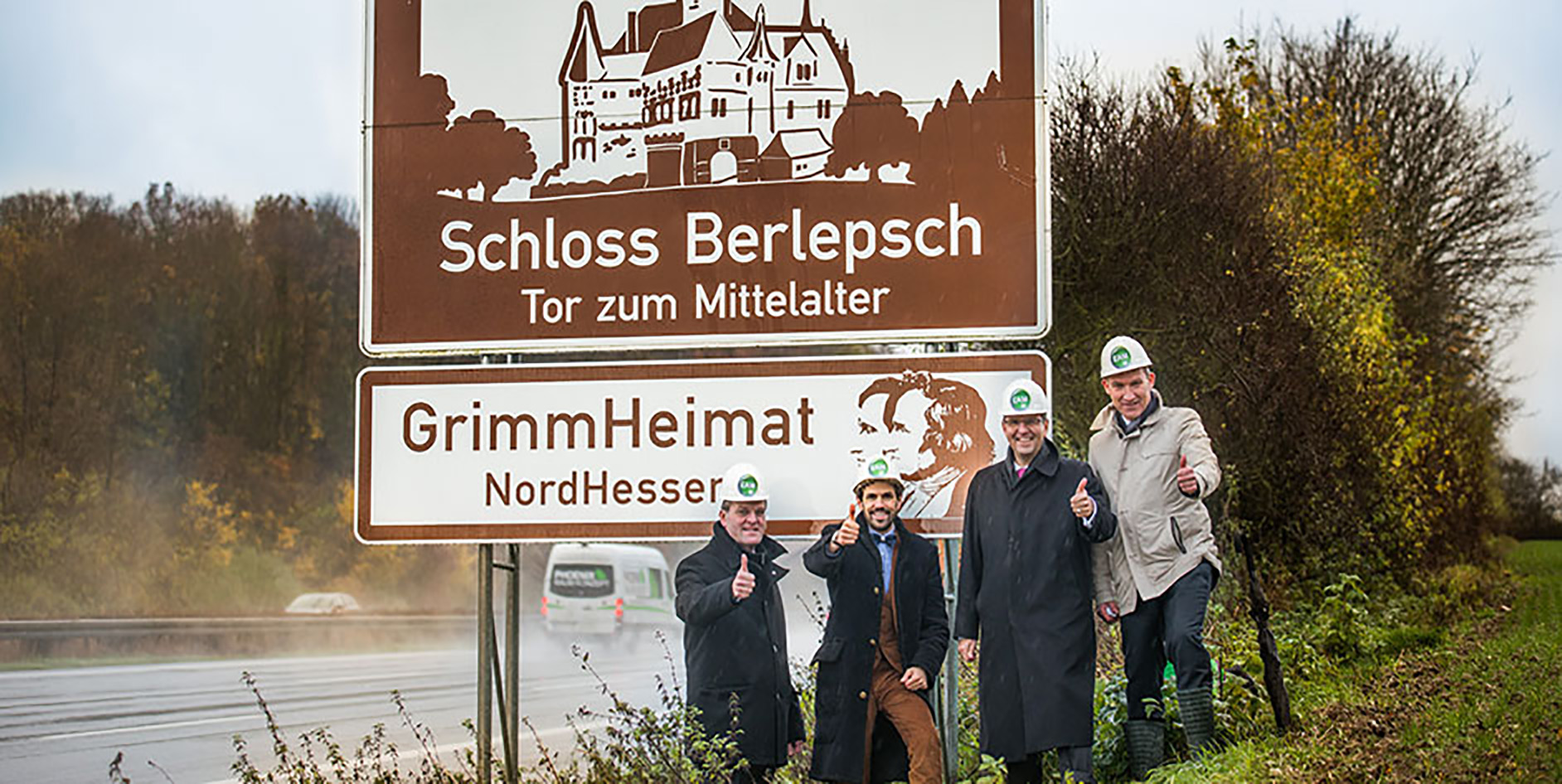 Vier Personen in Sicherheitshelmen stehen lächelnd neben einem Schild mit der Aufschrift Schloss Berlepsch – Tor zum Mittelalter.