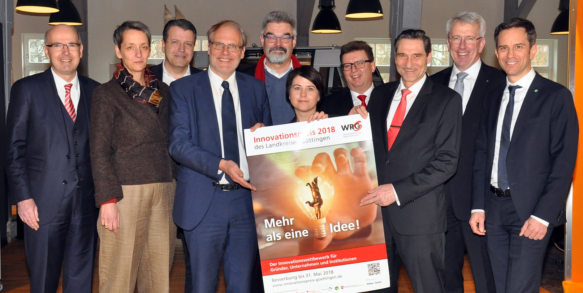 Gruppe von Personen hält ein Plakat zum Innovationspreis 2018 des Landkreises Göttingen, alle lächeln und schauen in die Kamera.