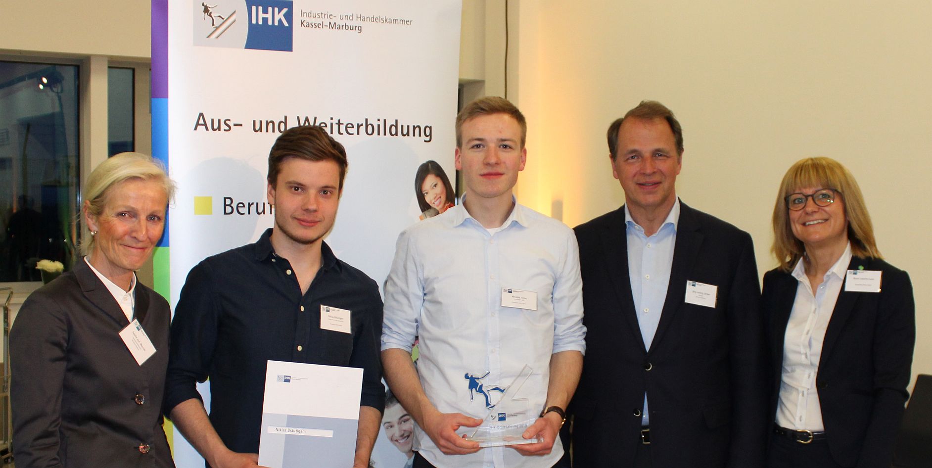 Fünf Personen stehen vor einem Banner der IHK Kassel-Marburg, das Informationen zur Aus- und Weiterbildung präsentiert.