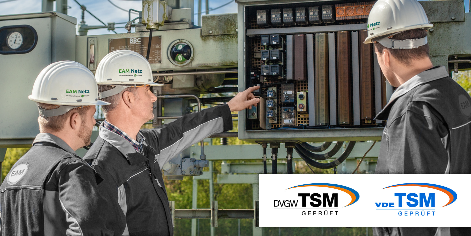 Drei Techniker mit Helmen analysieren elektrische Schaltanlagen in einem Umspannwerk. EAM Netz Logo sichtbar.