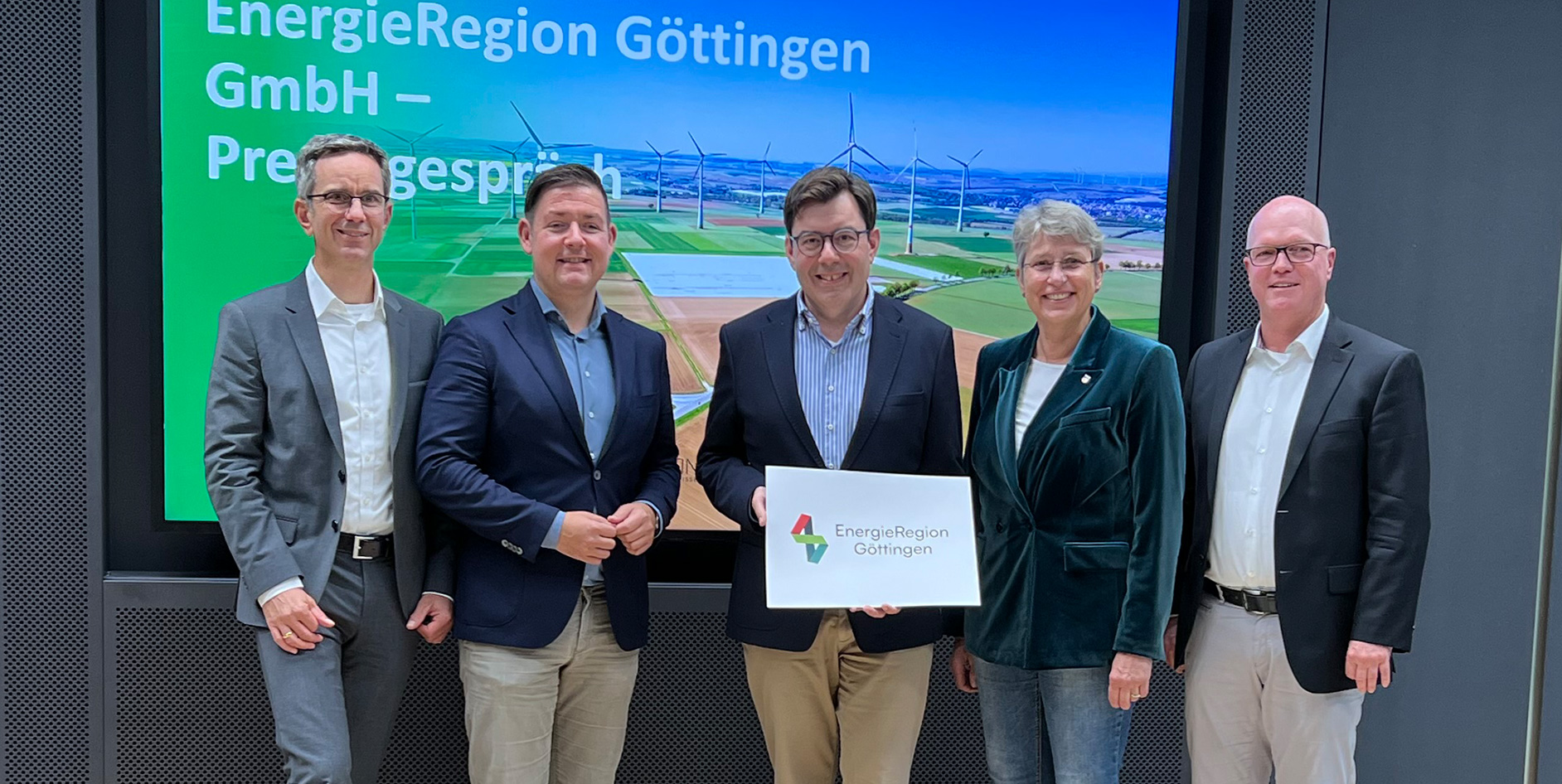 Gruppenfoto von fünf Personen vor einem Bildschirm mit dem Logo der EnergieRegion Göttingen und einer Landschaft mit Windrädern.