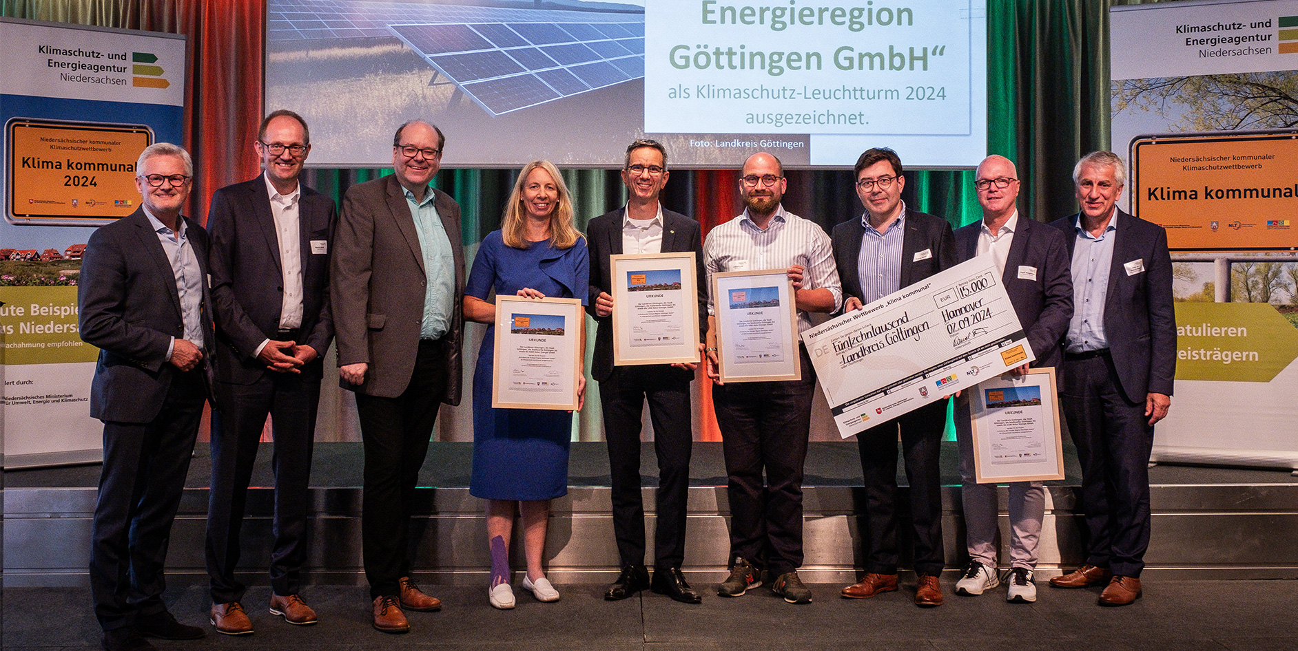 Gruppenfoto von Personen, die Urkunden und einen Scheck für den Klimaschutzwettbewerb 2024 präsentieren.